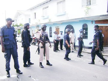 Police stand guard at the Lyken’s Funeral Home where the bodies of the three dead men were taken yesterday afternoon